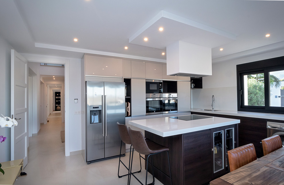 Diseño de cocina contemporánea con armarios con paneles lisos, electrodomésticos de acero inoxidable, una isla y encimeras blancas