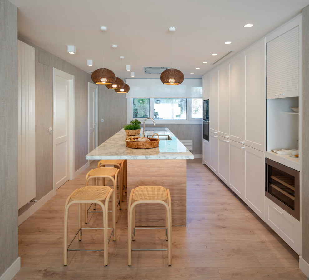 Immagine di una grande cucina classica con lavello sottopiano, ante con bugna sagomata, ante bianche, top in marmo, pavimento in legno massello medio, pavimento marrone e top bianco