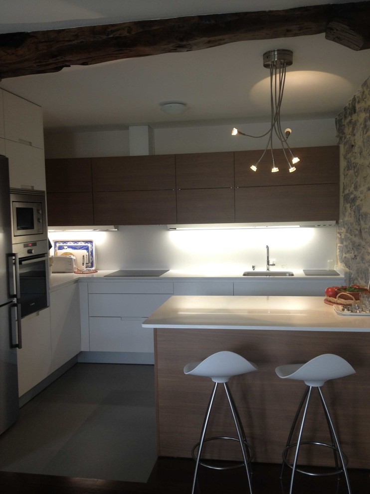 Modern inredning av ett mellanstort kök, med en enkel diskho, släta luckor, vita skåp, rostfria vitvaror, klinkergolv i keramik, en halv köksö, bänkskiva i kvarts, vitt stänkskydd och stänkskydd i sten