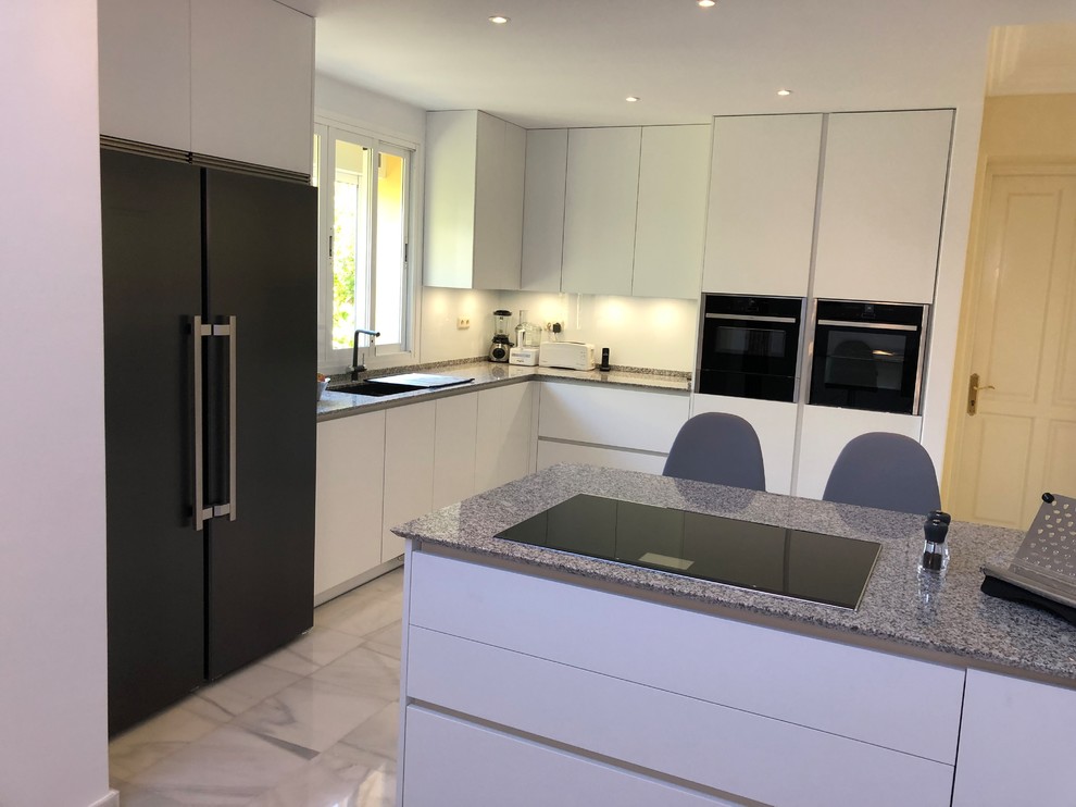 Inspiration for a large modern open plan kitchen in Other with a double-bowl sink, flat-panel cabinets, white cabinets, granite worktops, white splashback, window splashback, black appliances, marble flooring, a breakfast bar, white floors and grey worktops.