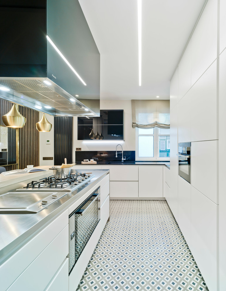 Foto på ett funkis grå kök, med släta luckor, vita skåp, bänkskiva i rostfritt stål, en köksö, en undermonterad diskho, rostfria vitvaror och flerfärgat golv