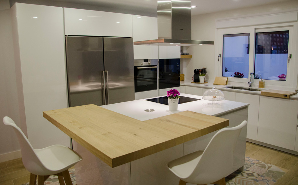 This is an example of a large scandinavian enclosed kitchen in Malaga with a submerged sink, white cabinets, engineered stone countertops, stainless steel appliances, porcelain flooring, an island, brown floors and white worktops.