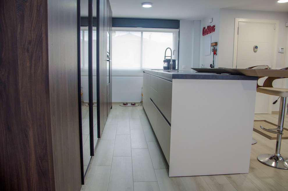 Photo of a large modern galley kitchen/diner in Malaga with a belfast sink, glass-front cabinets, brown cabinets, black appliances, porcelain flooring, an island, beige floors and brown worktops.