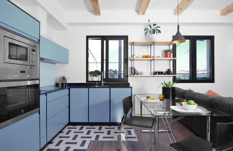 На фото: угловая кухня-гостиная среднего размера в стиле модернизм с плоскими фасадами и синими фасадами без острова с