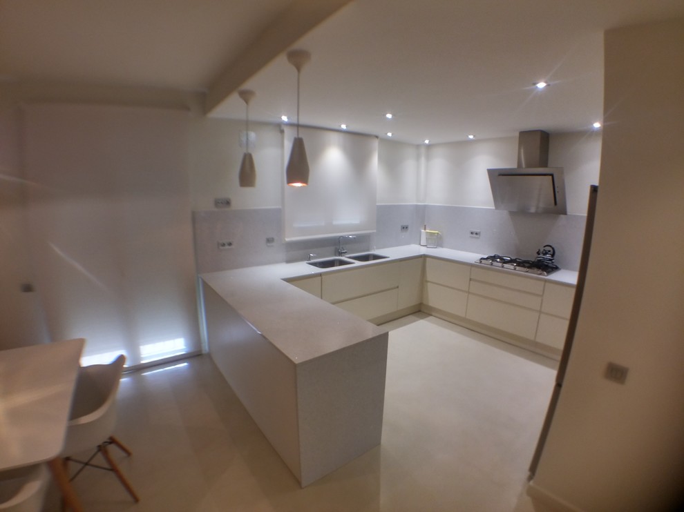 Immagine di una cucina ad U design di medie dimensioni con ante lisce, pavimento in cemento, lavello a doppia vasca, ante bianche e penisola