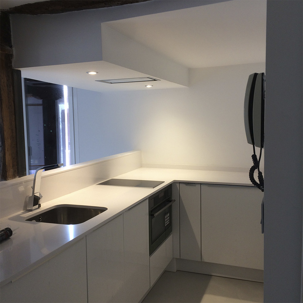 Modern inredning av ett litet kök, med en undermonterad diskho, luckor med infälld panel, vita skåp, bänkskiva i terrazo, vitt stänkskydd, rostfria vitvaror, betonggolv och grått golv