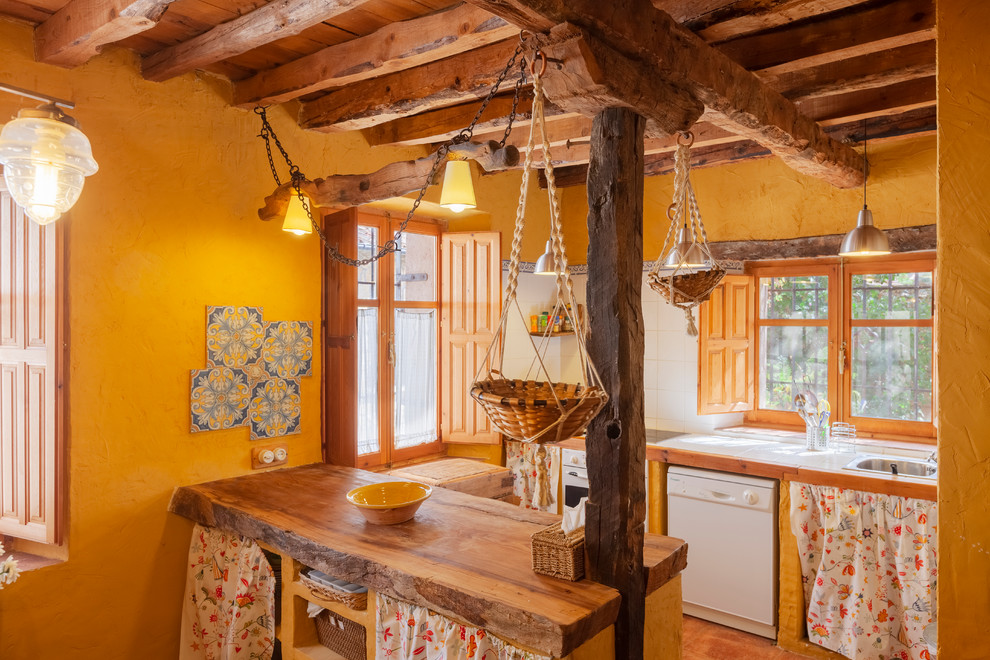 Landhaus Küche mit Einbauwaschbecken, hellbraunen Holzschränken, Arbeitsplatte aus Holz, Rückwand-Fenster, weißen Elektrogeräten und Halbinsel in Madrid