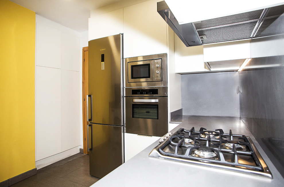 Idéer för att renovera ett mellanstort funkis u-kök, med en enkel diskho, vita skåp, grått stänkskydd, rostfria vitvaror och mellanmörkt trägolv