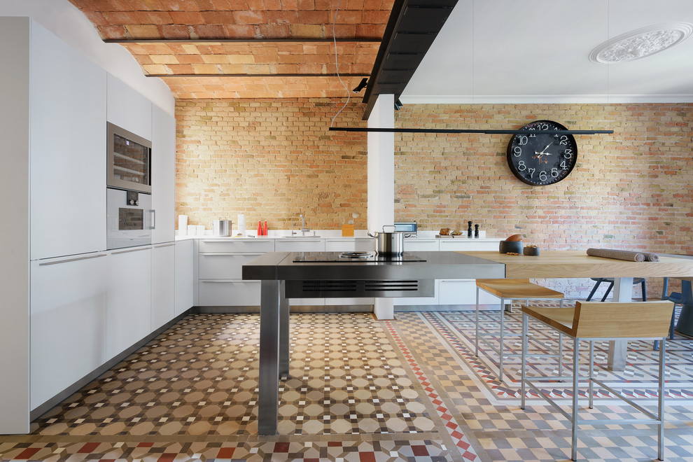 Mediterrane Küche in L-Form mit flächenbündigen Schrankfronten, weißen Schränken, Edelstahl-Arbeitsplatte, Kücheninsel und buntem Boden in Barcelona