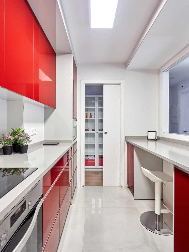 Example of a small trendy galley porcelain tile and gray floor enclosed kitchen design in Other with flat-panel cabinets, red cabinets, white backsplash, porcelain backsplash, stainless steel appliances, no island and gray countertops