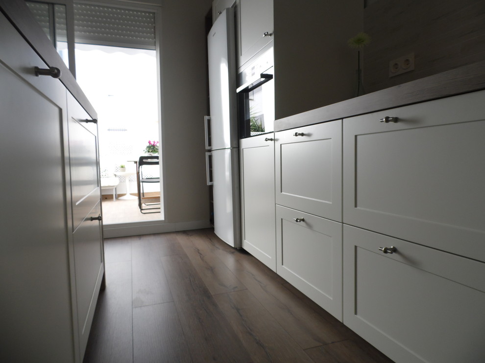 Imagen de cocina comedor lineal escandinava de tamaño medio con puertas de armario blancas, una isla, armarios con paneles empotrados, encimera de madera, salpicadero blanco y suelo de madera en tonos medios