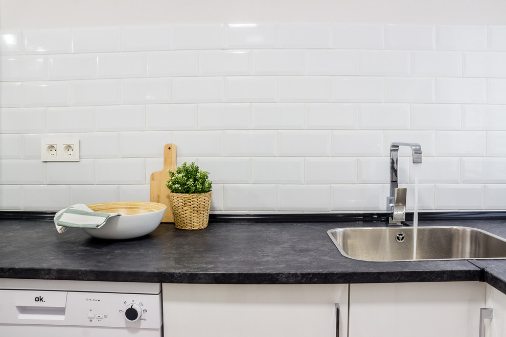 Foto di una piccola cucina design con lavello da incasso, ante lisce, ante bianche, top in laminato, elettrodomestici in acciaio inossidabile, pavimento in laminato e top nero