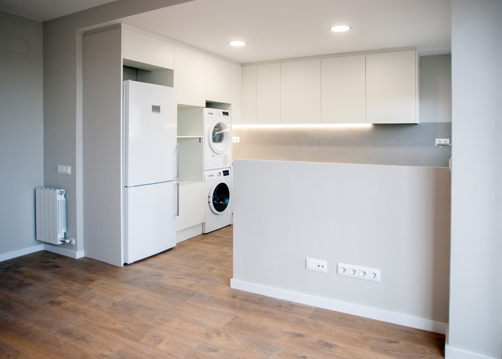 Example of a mid-sized trendy u-shaped medium tone wood floor and brown floor open concept kitchen design in Barcelona with a single-bowl sink, white cabinets, gray backsplash, white appliances, no island and white countertops