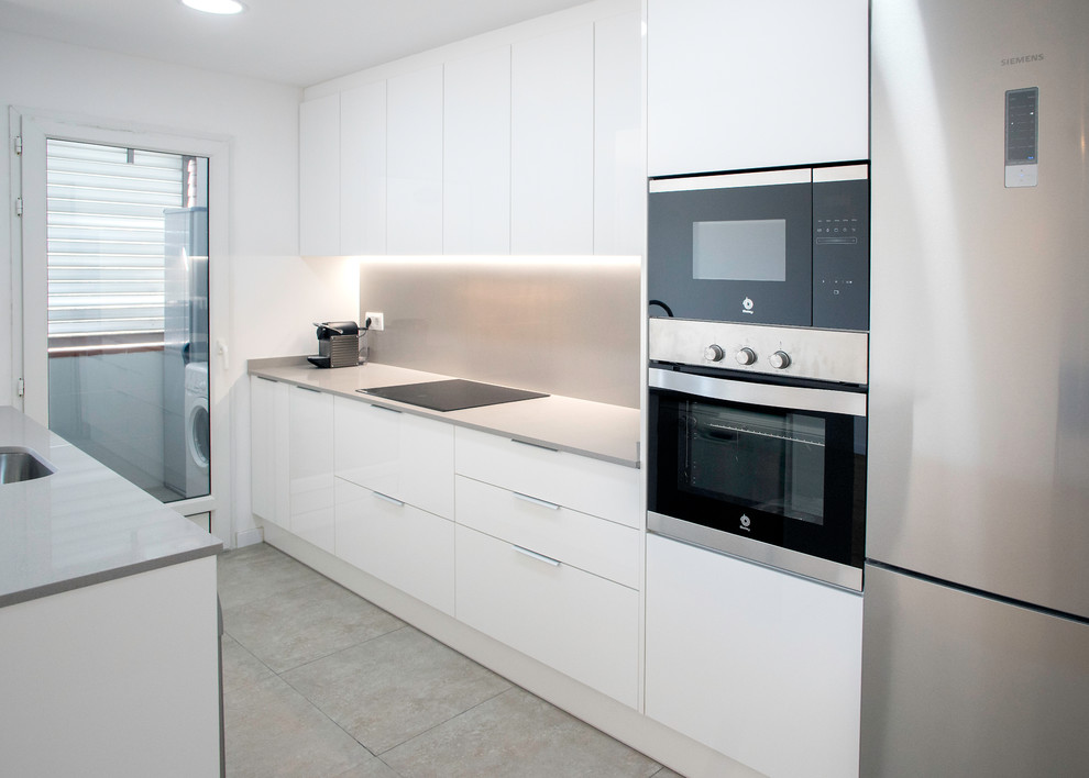 Bild på ett mellanstort funkis grå grått kök, med en enkel diskho, vita skåp, grått stänkskydd, rostfria vitvaror och grått golv