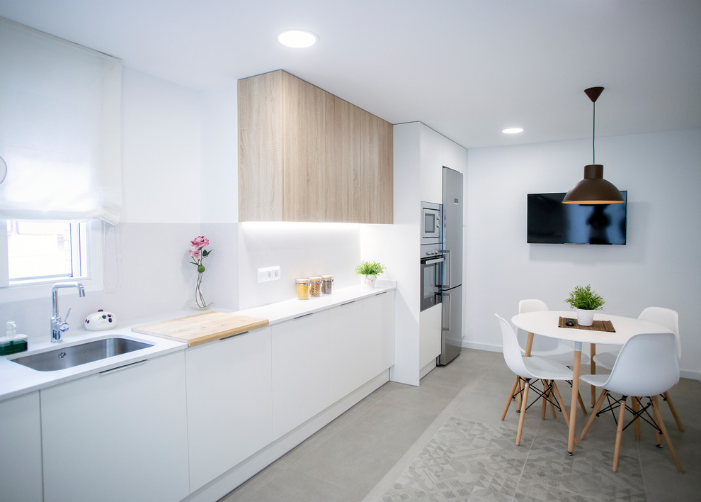 Idéer för ett stort modernt vit linjärt kök och matrum, med en enkel diskho, släta luckor, vita skåp, vitt stänkskydd, rostfria vitvaror och grått golv
