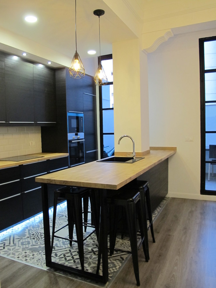 Foto de cocina comedor urbana con fregadero de un seno, puertas de armario negras, encimera de madera, suelo de madera clara, una isla y suelo gris