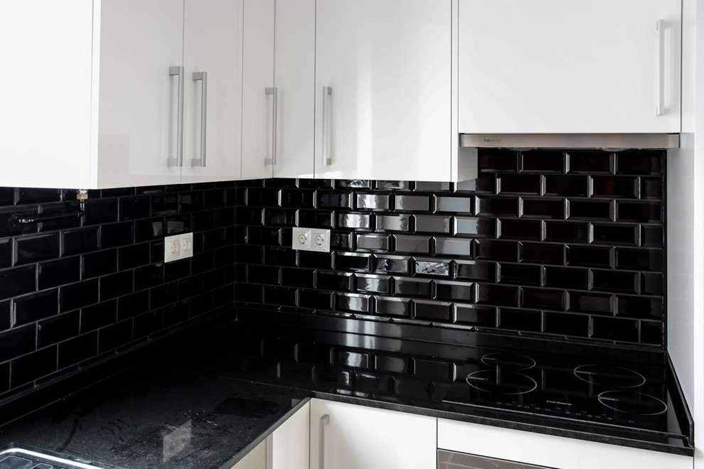 Modern inredning av ett mellanstort kök, med en nedsänkt diskho, släta luckor, vita skåp, granitbänkskiva, svart stänkskydd, stänkskydd i keramik, rostfria vitvaror och laminatgolv