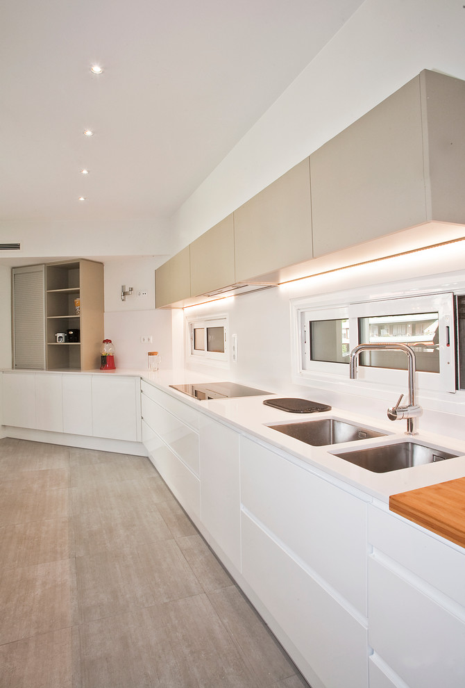 Foto på ett stort funkis linjärt kök med öppen planlösning, med en dubbel diskho, vita skåp, vitt stänkskydd, rostfria vitvaror, mellanmörkt trägolv och släta luckor