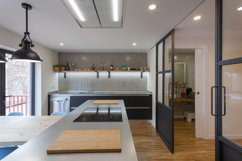 Idéer för att renovera ett avskilt, mellanstort industriellt grå linjärt grått kök, med en integrerad diskho, luckor med infälld panel, svarta skåp, bänkskiva i onyx, grått stänkskydd, rostfria vitvaror, mellanmörkt trägolv, en köksö och brunt golv