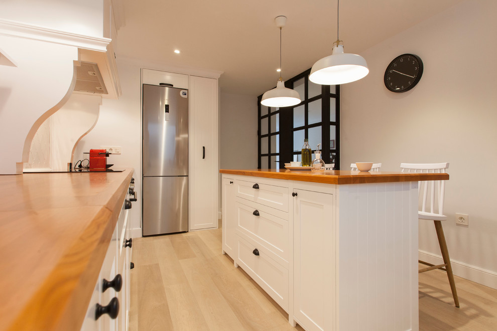 Immagine di una cucina scandinava di medie dimensioni con ante con riquadro incassato, ante bianche, top in legno, paraspruzzi bianco e parquet chiaro