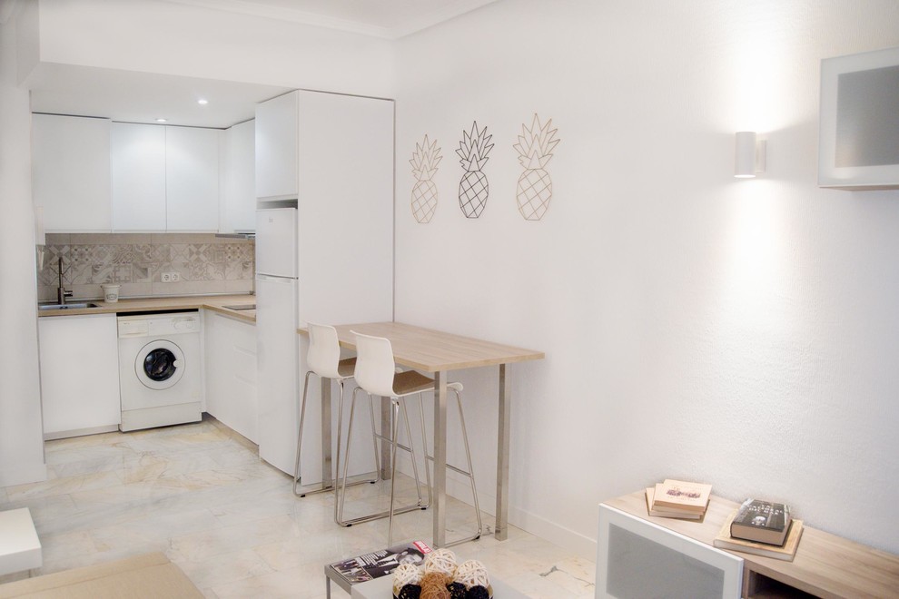 Minimalistisk inredning av ett litet brun brunt kök, med en enkel diskho, släta luckor, vita skåp, laminatbänkskiva, beige stänkskydd, stänkskydd i keramik, vita vitvaror, marmorgolv och vitt golv