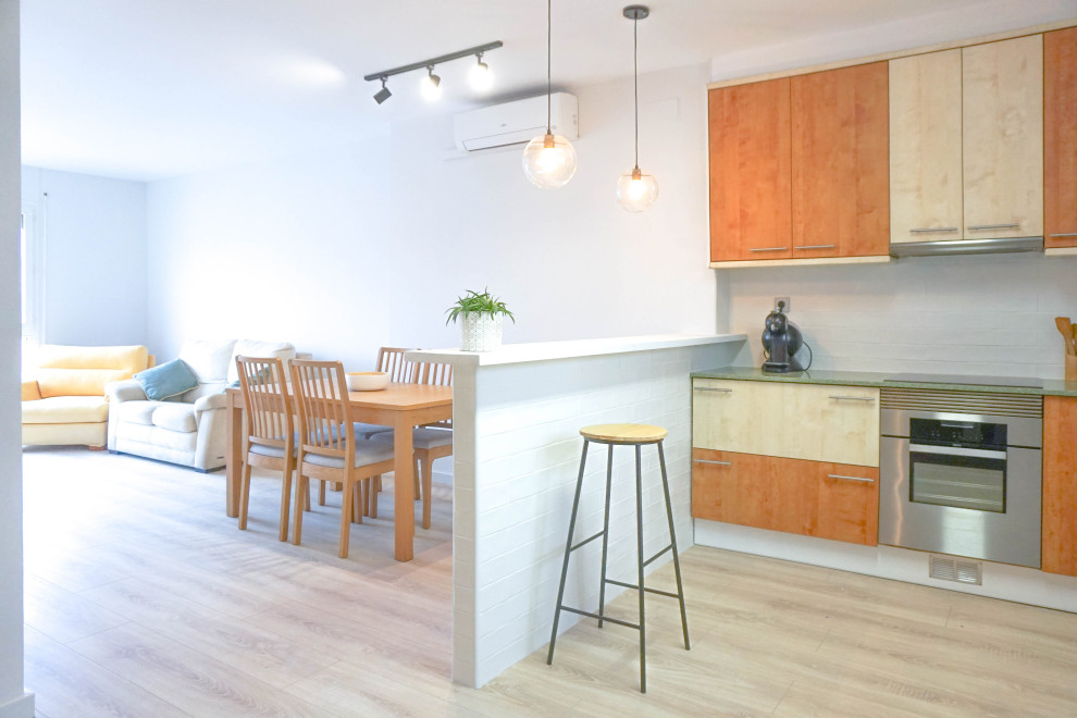 Modern inredning av ett mellanstort flerfärgad flerfärgat kök, med en dubbel diskho, släta luckor, skåp i ljust trä, marmorbänkskiva, vitt stänkskydd, stänkskydd i keramik, rostfria vitvaror, ljust trägolv, en halv köksö och beiget golv