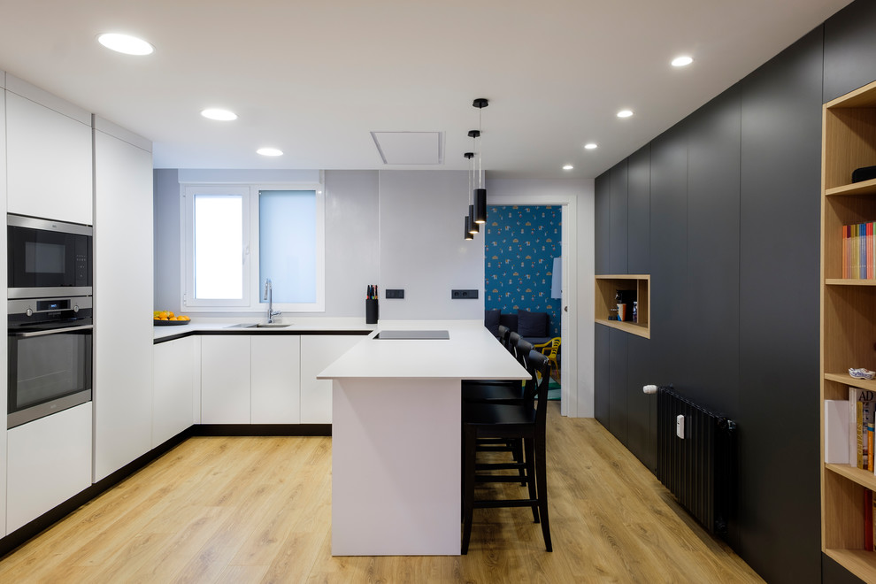 Large contemporary u-shaped kitchen/diner in Other with a submerged sink, white cabinets, engineered stone countertops, integrated appliances, laminate floors, a breakfast bar, beige floors, white worktops and flat-panel cabinets.