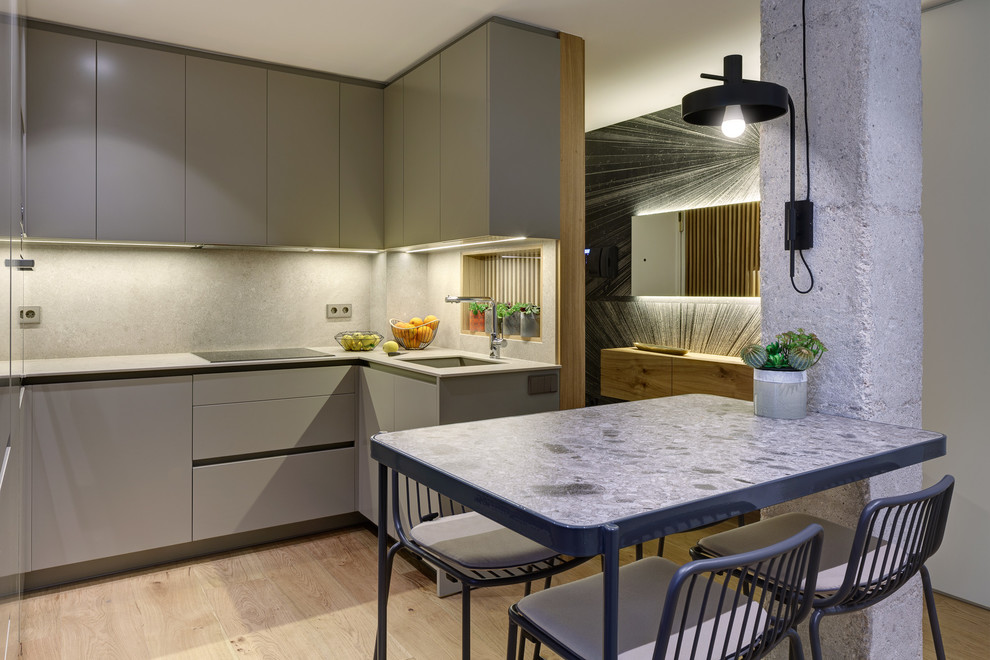 Mid-sized trendy u-shaped light wood floor and beige floor eat-in kitchen photo in Alicante-Costa Blanca with an undermount sink, flat-panel cabinets, gray cabinets, gray backsplash, gray countertops, paneled appliances and no island