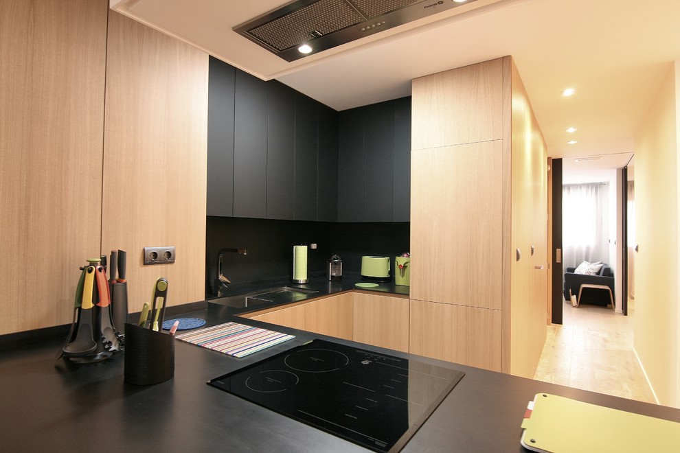 Ejemplo de cocinas en U moderno pequeño abierto con armarios con paneles lisos, puertas de armario negras y península