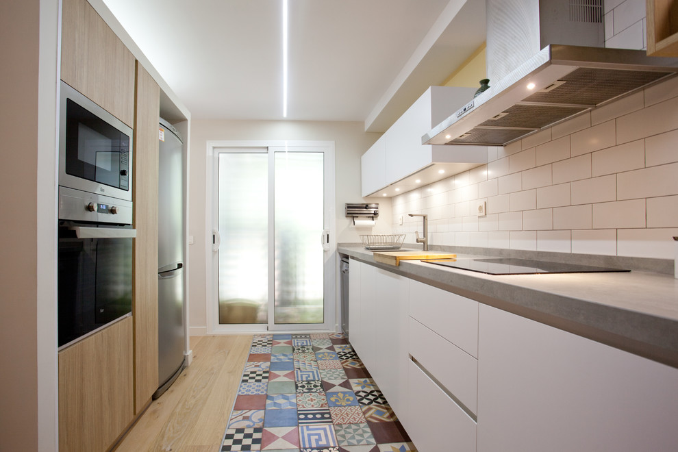 Imagen de cocina lineal contemporánea abierta con fregadero bajoencimera, armarios con paneles lisos, puertas de armario blancas y electrodomésticos de acero inoxidable