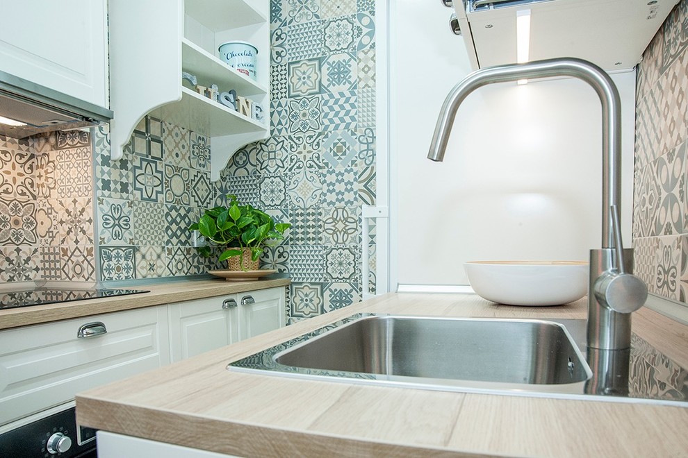 Foto di una piccola cucina scandinava con ante a filo, ante bianche, top in legno, paraspruzzi multicolore, elettrodomestici bianchi, pavimento in gres porcellanato e top marrone