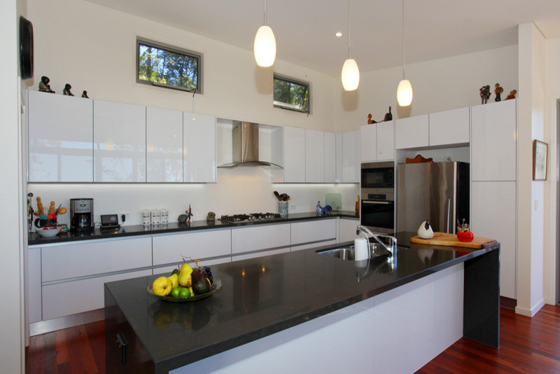 Esempio di una cucina minimalista di medie dimensioni con ante lisce, ante bianche, paraspruzzi bianco, elettrodomestici in acciaio inossidabile e parquet scuro