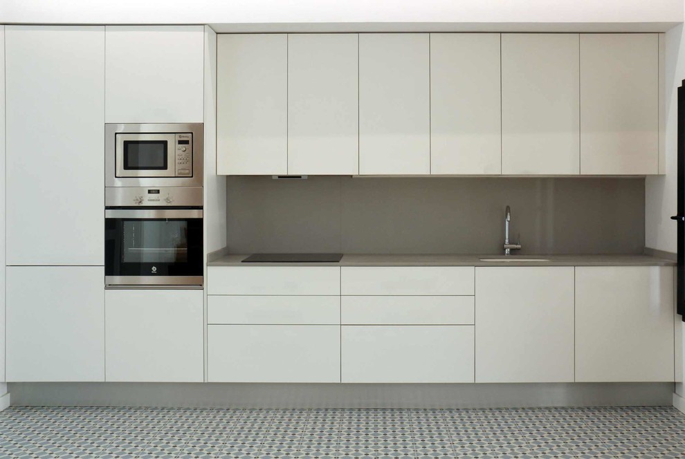 Bild på ett avskilt, mellanstort funkis linjärt kök, med släta luckor, vita skåp, brunt stänkskydd, rostfria vitvaror, klinkergolv i keramik och en undermonterad diskho