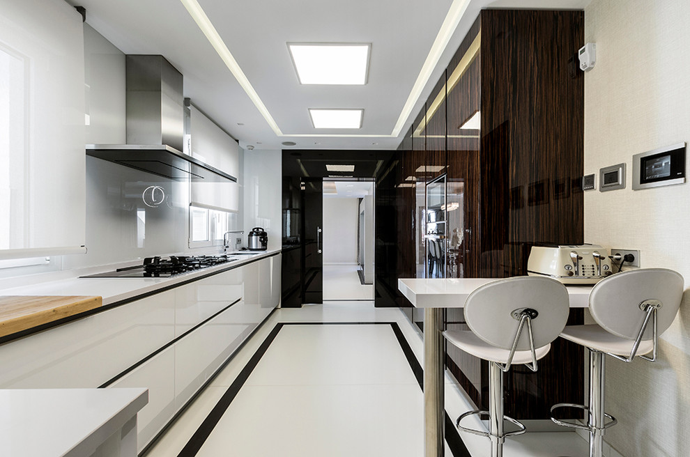На фото: отдельная кухня среднего размера в современном стиле с врезной мойкой, плоскими фасадами, белым фартуком, полуостровом, черно-белыми фасадами и барной стойкой