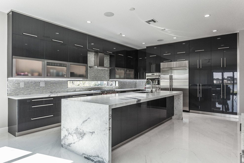 Expansive contemporary l-shaped kitchen with an undermount sink, flat-panel cabinets, metallic splashback, stainless steel appliances, ceramic floors, with island, white floor, grey benchtop, black cabinets and mosaic tile splashback.