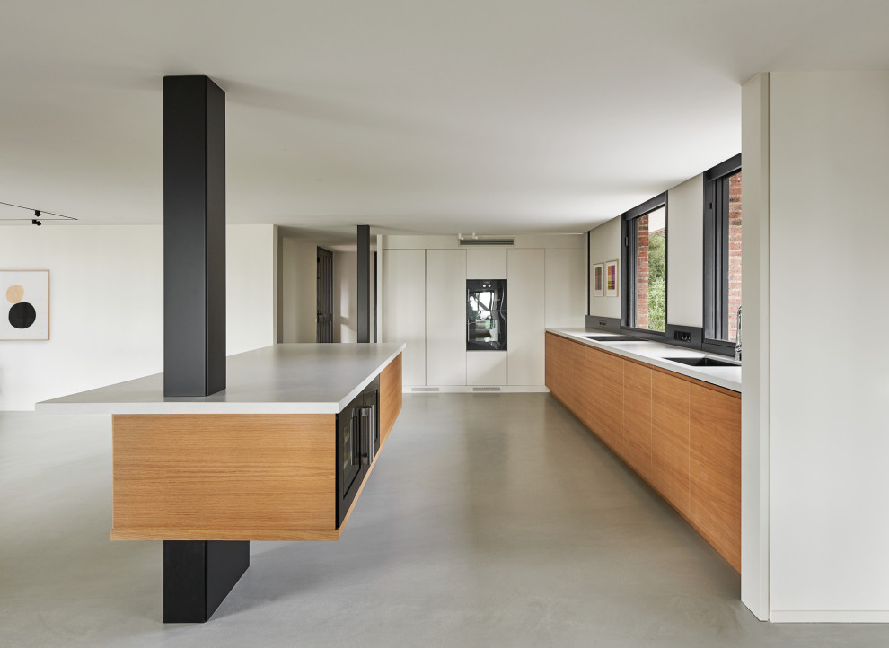 Photo of a large l-shaped open plan kitchen in Barcelona with an integrated sink, recessed-panel cabinets, light wood cabinets, engineered stone countertops, black splashback, wood splashback, black appliances, concrete flooring, an island, grey floors, grey worktops and a coffered ceiling.