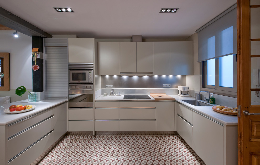 Пример оригинального дизайна: п-образная кухня-гостиная среднего размера в современном стиле с одинарной мойкой, плоскими фасадами, белыми фасадами, техникой из нержавеющей стали, полом из керамической плитки и полуостровом