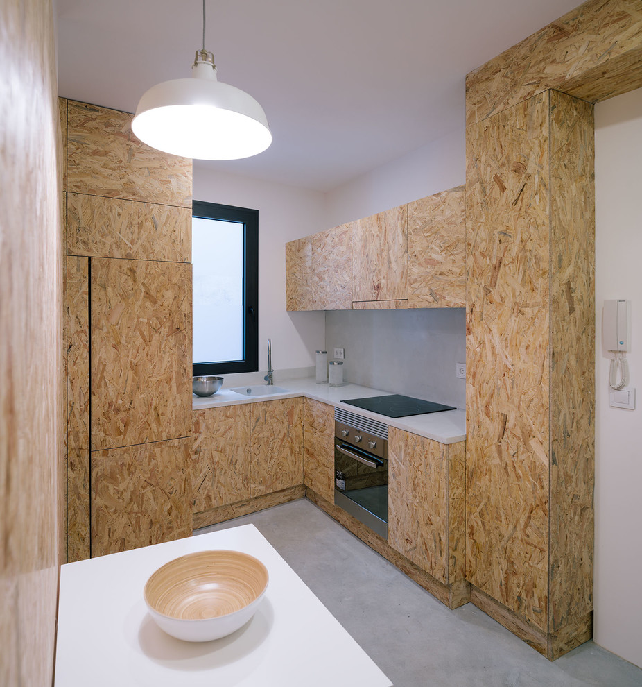 Kleine Industrial Wohnküche ohne Insel in L-Form mit integriertem Waschbecken, hellbraunen Holzschränken, Küchengeräten aus Edelstahl, Betonboden, flächenbündigen Schrankfronten und weißer Arbeitsplatte in Madrid