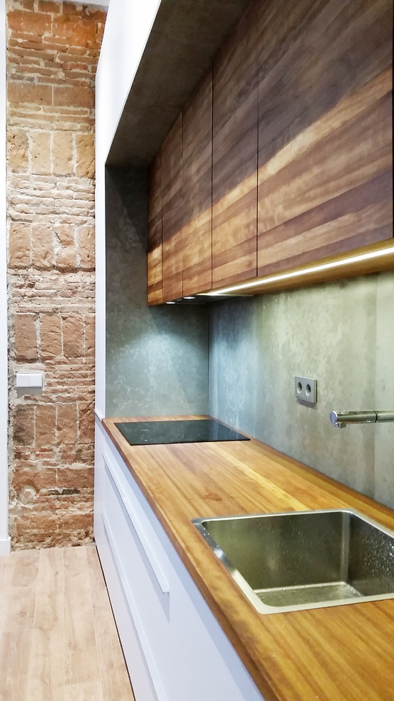 Réalisation d'une cuisine ouverte linéaire design en bois brun de taille moyenne avec un placard à porte plane, un plan de travail en bois, une crédence grise, un électroménager en acier inoxydable et un sol en bois brun.