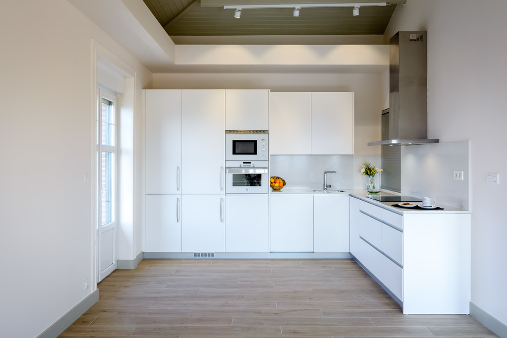 Moderne Küche mit flächenbündigen Schrankfronten, weißen Schränken, Küchenrückwand in Weiß und weißer Arbeitsplatte in Bilbao