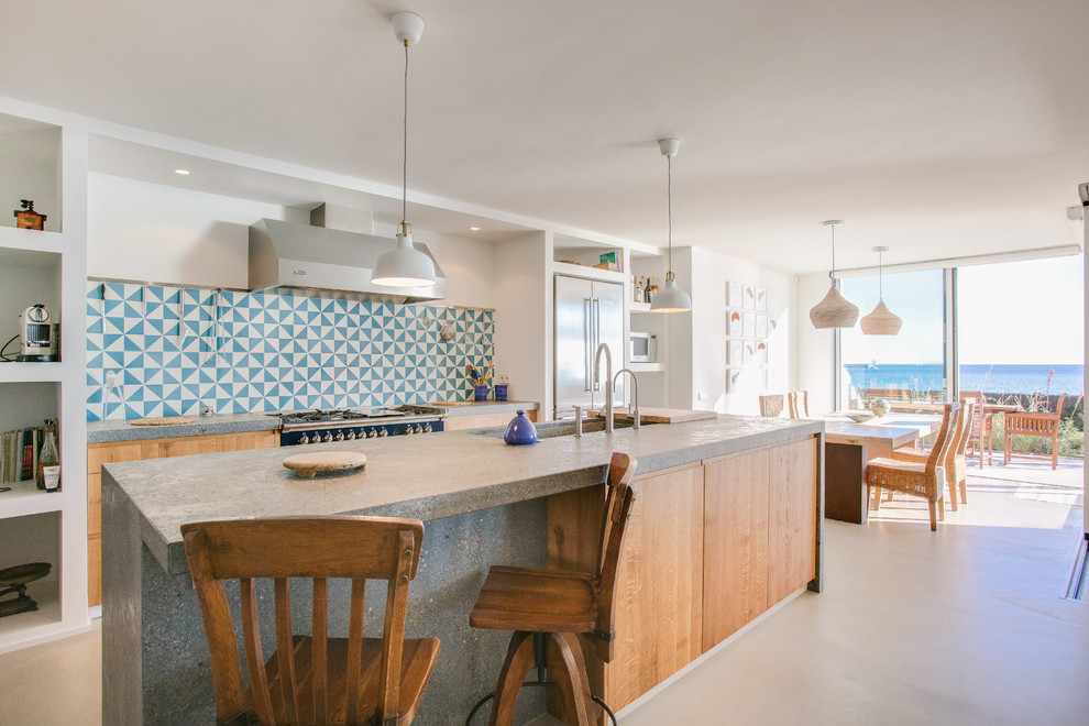 Inspiration for a coastal galley kitchen/diner in Barcelona with flat-panel cabinets, medium wood cabinets, concrete worktops, multi-coloured splashback, stainless steel appliances, concrete flooring, an island and grey floors.