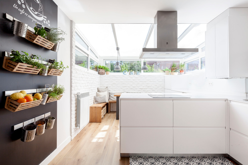 Mittelgroße Moderne Küche mit flächenbündigen Schrankfronten, weißen Schränken, Halbinsel, hellem Holzboden, beigem Boden und Küchenrückwand in Weiß in Madrid
