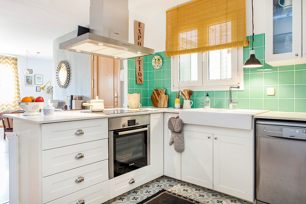 Photo of a medium sized retro l-shaped open plan kitchen in Barcelona with a built-in sink, recessed-panel cabinets, white cabinets, green splashback, cement tile splashback, stainless steel appliances, ceramic flooring and no island.