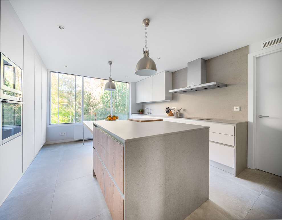 This is an example of a large modern galley enclosed kitchen in Madrid with flat-panel cabinets, white cabinets, stainless steel appliances, an island, grey splashback, composite countertops and ceramic flooring.