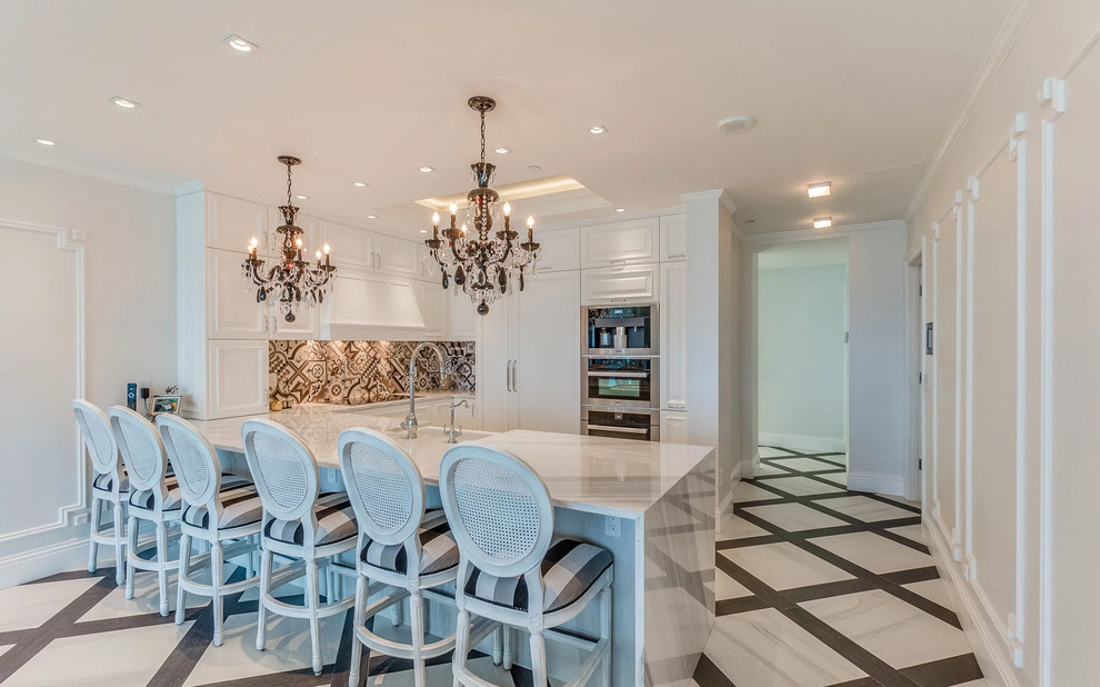 Transitional u-shaped gray floor kitchen photo in Miami with a farmhouse sink, white cabinets, multicolored backsplash, mosaic tile backsplash, a peninsula and white countertops