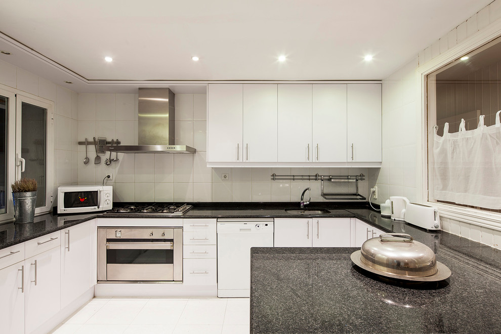 Large classic u-shaped enclosed kitchen in Madrid with flat-panel cabinets, white cabinets, granite worktops, white splashback, stainless steel appliances and a breakfast bar.