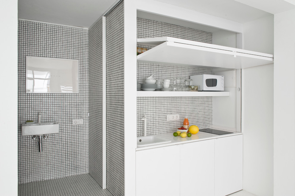 Ejemplo de cocina lineal actual pequeña abierta sin isla con armarios con paneles lisos y puertas de armario blancas