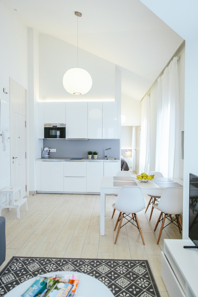 Immagine di una piccola cucina design con ante lisce, ante bianche, paraspruzzi grigio, elettrodomestici da incasso, parquet chiaro e nessuna isola