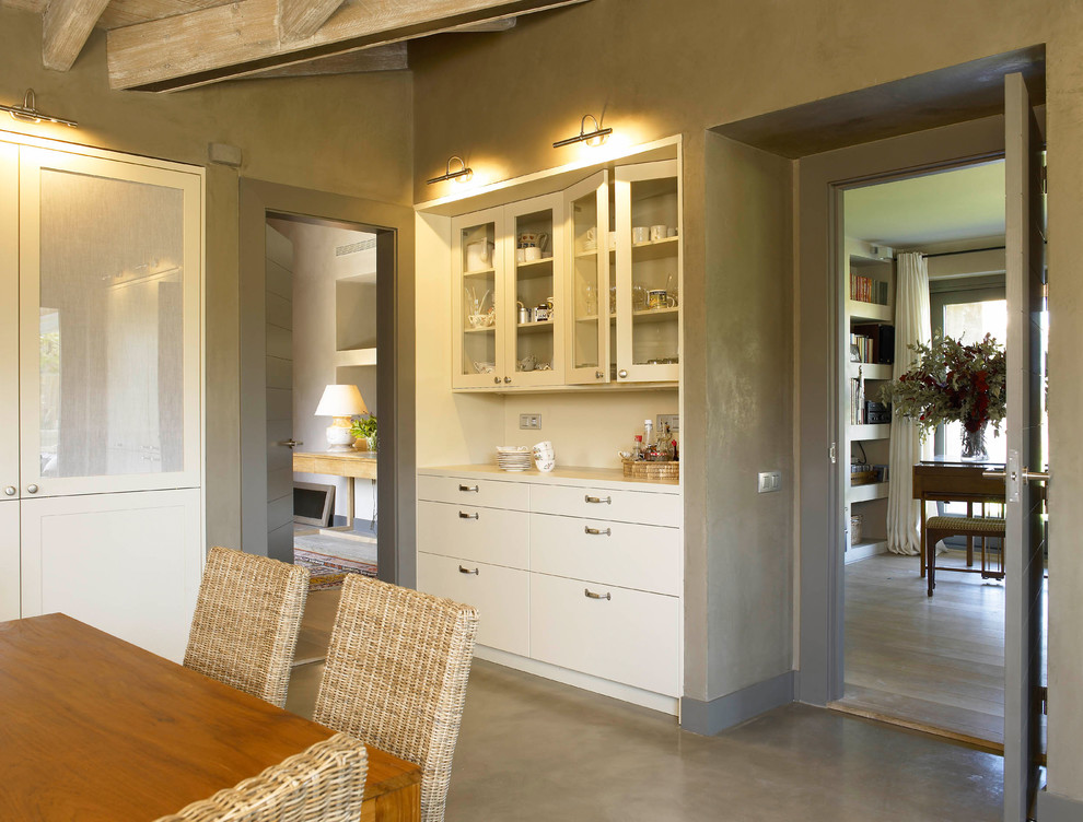 Foto på ett lantligt kök och matrum, med en dubbel diskho, släta luckor, vita skåp, vitt stänkskydd, rostfria vitvaror och betonggolv