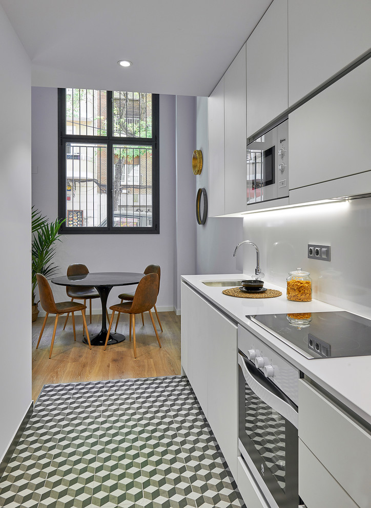 Réalisation d'une cuisine linéaire minimaliste avec un évier encastré, un placard à porte plane, des portes de placard blanches et un plan de travail blanc.